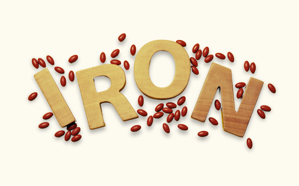 Picture of iron spelled in wood blocks with red pills surrounding it